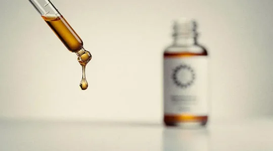 Gota de sérum facial cayendo de un cuentagotas de vidrio, simbolizando el análisis de la concentración real de activos