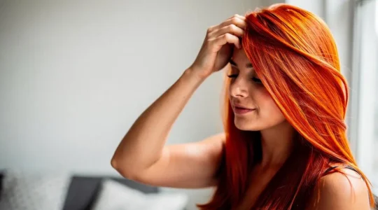 Mujer con cabello recien tenido de color vibrante bajo luz natural, simbolo del cuidado post-tinte