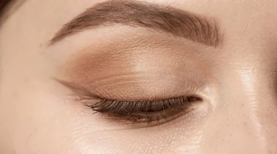 Primer plano editorial de un ojo femenino con sombras difuminadas en degradado, mostrando una transición de color perfecta en el párpado
