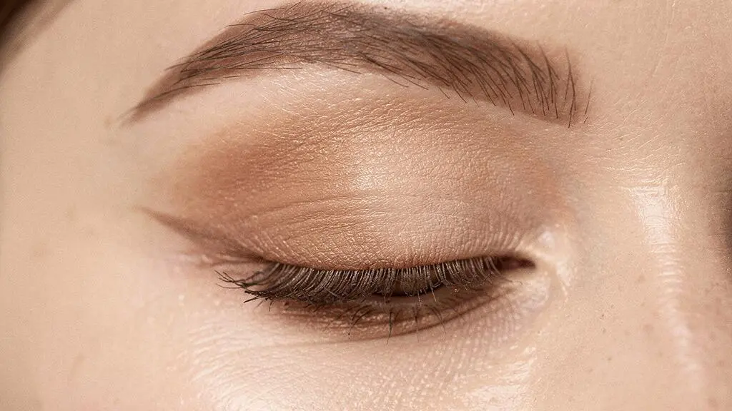 Primer plano editorial de un ojo femenino con sombras difuminadas en degradado, mostrando una transición de color perfecta en el párpado