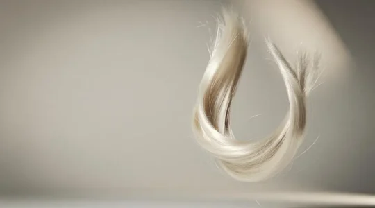 Mechon de cabello rubio platino con reflejos luminosos que simboliza el equilibrio entre la decoloracion extrema y la salud capilar