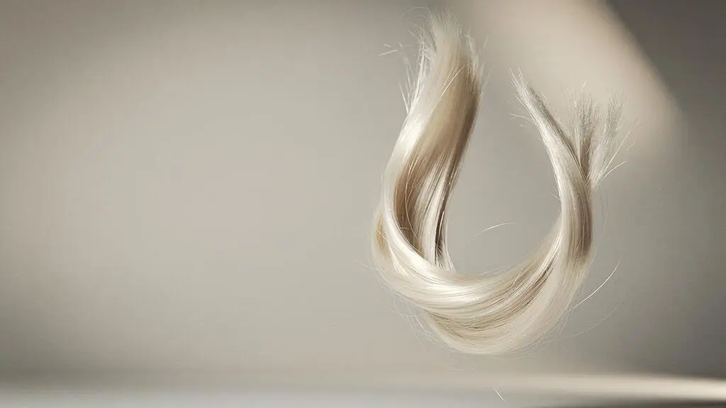 Mechon de cabello rubio platino con reflejos luminosos que simboliza el equilibrio entre la decoloracion extrema y la salud capilar