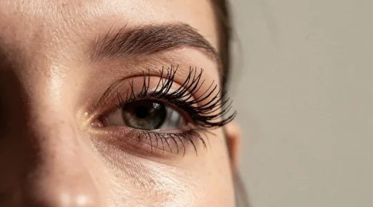 Primer plano editorial de un ojo femenino con pestañas naturales bien definidas que ilustra la elección de máscara según su grosor y longitud