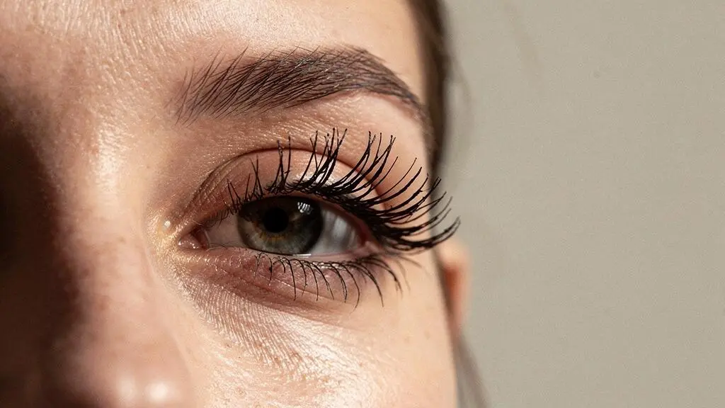 Primer plano editorial de un ojo femenino con pestañas naturales bien definidas que ilustra la elección de máscara según su grosor y longitud