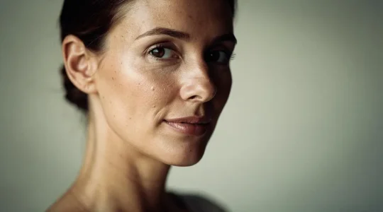 Mujer con piel luminosa y saludable iluminada por luz natural suave, simbolizando la prevencion del envejecimiento prematuro