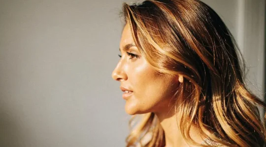 Mujer con cabello castano y reflejos dorados naturales iluminados por luz solar suave, efecto sunkissed