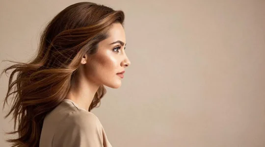 Mujer con cabello teñido de forma saludable, mostrando brillo natural y color uniforme en un ambiente editorial luminoso